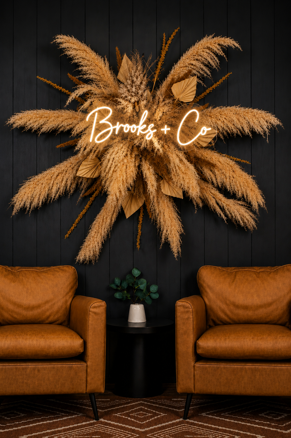 The Brooks + Co neon sign with pampas grass and leather chairs in the studio interior